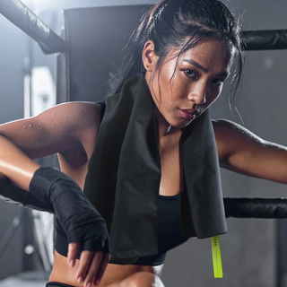Woman in a Gym Setting wearing the TRNR Quick-Dry Towel in Black/Lime around her Neck